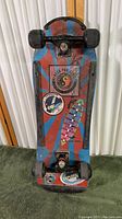 Skateboard top-down photo showing the graphic design and stickers on the deck, worn condition visible.