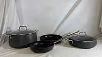Four piece All-Clad cookware set with stockpot, sauté pan, saucepan, and frying pan, displayed to show scale and components.