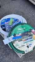 View showing coiled green reinforced garden hose and two white boat hoses with packaging labels.