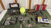 View showing the full layout of tools including Rigid pipe threader, yellow hard hat, pliers, scrapers, measuring tape, pipe wrenches and red hardware organizer boxes.