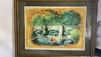 Front view of framed art print showing colorful autumnal landscape with a stone bridge over a creek.