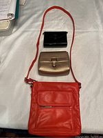 Top view of all three purses; orange Giani Bernini crossbody, gold Lauren Ralph Lauren purse, black patent small purse