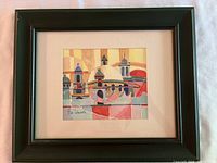 Framed watercolour painting showing cityscape with domes and towers in bright colors, signed by Bill Schwartz.