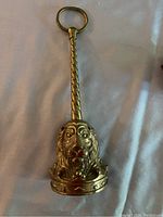 Brass door stop showing twisted handle with rounded top loop and lion face base, front angle.