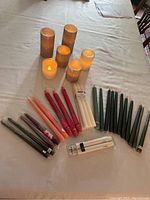 All candles laid out on a beige surface showing various sizes and colors along with packaging.
