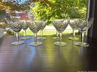 8 crystal sherry glasses with patterned designs, seen in natural light, showing clear cut glass details and uniform size.