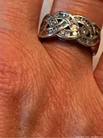 Ring worn on finger, showing front view of three-strand braid design with channel set diamonds.