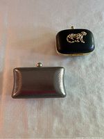 Two evening bags side by side: black with jewelled leopard and silver clutch