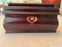 Closed view of dark mahogany wood jewellery box showing decorative brass lock.