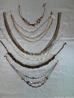 Top-down view showing all six necklaces laid flat, displaying various metal tones and chain styles.