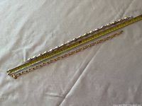 Photo showing two necklaces side by side with measuring tape, silver-gold necklace is longer around 20 inches, gold tone bronze necklace shorter, about 18 inches