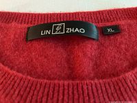 Close up of black fabric brand label "LIN ZHAO" with size XL