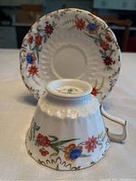 Photo of cup and saucer set with visible floral pattern and gold decorative accents