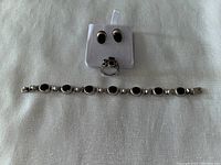 Front view of the entire jewelry set laid out, showing bracelet, ring, and earrings on white background.