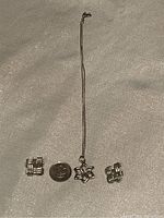 Full set displayed with quarter for size reference: sterling silver necklace with flower pendant and pair of square sterling silver earrings.