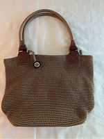 Front view of the beige woven handbag with leather handles showing overall condition and shape.