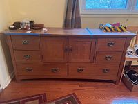Front view of the Bassett wooden triple dresser with six drawers and two cabinet doors.