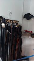 Full view of assorted belts hanging on a rack, various widths, and materials