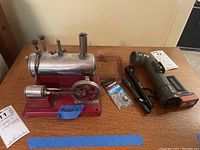 Photo of metal model engine and four flashlights laid out on table showing engine details and flashlights.