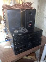 Overall view of stacked JVC receiver and CD changer, Infinity speakers on top, speaker wire coiled around one speaker, two remotes on CD changer.