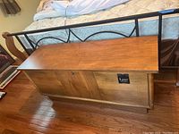 Closed cedar chest showing wood finish and black label on front panel.