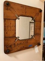 Wood framed mirror with dark wood and sewing pattern style markings, square mirror in center.