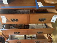 Two open wooden drawers containing US Navy booklets and insignia items