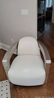 Front view of white leather lounge chair showing seat cushion, backrest, and chrome arms