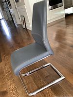Side view of one grey leather dining chair showing upholstery and chrome cantilever base