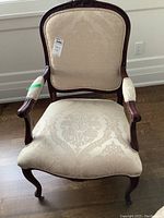 Front view of captain’s chair showing carved crest and damask upholstery