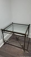 Photo of the metal frame side table with clear glass top showing the corner and decorative legs.