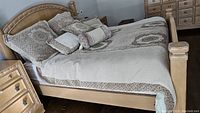 Full view of bed made with West Elm bedding including king duvet and various decorative pillow covers on wooden bed frame.
