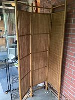 Full view of the three-section bamboo folding screen standing upright indoors, showing its natural bamboo frame and woven bamboo panel construction.