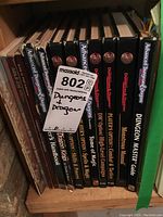 Shelf view showing six black-spined TSR hardcover AD&D 2nd Edition books with gold logos and a small red-spined volume at left.
