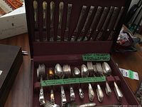Full view of open wooden canteen with a total of 55 silver plated cutlery pieces including knives, forks, teaspoons, and dessert spoons in two distinct handle patterns, with labels identifying quantities.