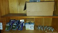 Shelf with cardboard box, sealed Ral Partha packets at left and loose grey miniatures at right
