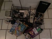 Overview photo showing the full collection of grooming items including hair clipper, curling iron, toothbrush, razor, and hair accessories organized in metal baskets on tiled floor.
