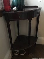 Side view of vintage wooden corner table showing shape, legs, and bottom shelf