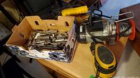 Electric winch, Dewalt palm sander, and Bayco lamp visible along with a box containing sockets and wrenches.