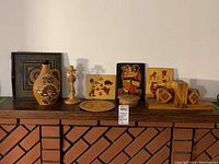 Full assortment of Ukrainian wood art and decorative ceramic jug displayed on wooden shelf against white wall