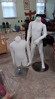 Photo showing both mannequins side by side in a room, illustrating their relative sizes and bases