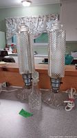 Pair of glass lamps and glass bottle on countertop