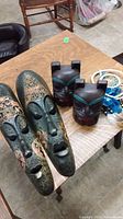 Photo of two elongated carved wood masks with painted tribal designs and two stylized carved wood animal bookends on a wooden table.