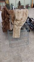 Front view of the clothes drying rack with the two fur wraps draped over it.