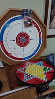 Tin checkerboard, wooden octagonal backgammon board with numbered scoring, and colorful wooden star tray game with bag of playing pieces