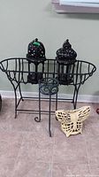 Photo showing metal plant stand, metal planter, two metal lanterns, and cast metal butterfly.