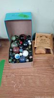 Box of assorted marbles of various colors and sizes alongside wooden yoyo box