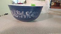 Photo showing blue mixing bowl with white Colonial Mist floral pattern on the outside, placed on countertop