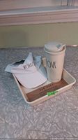 Photo showing white ceramic mug with 'LOVE' lettering, white plastic lid, and white visor hat with 'WORKOUT'