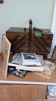 Wooden tiered sewing basket on shelf with sewing and quilting books underneath
